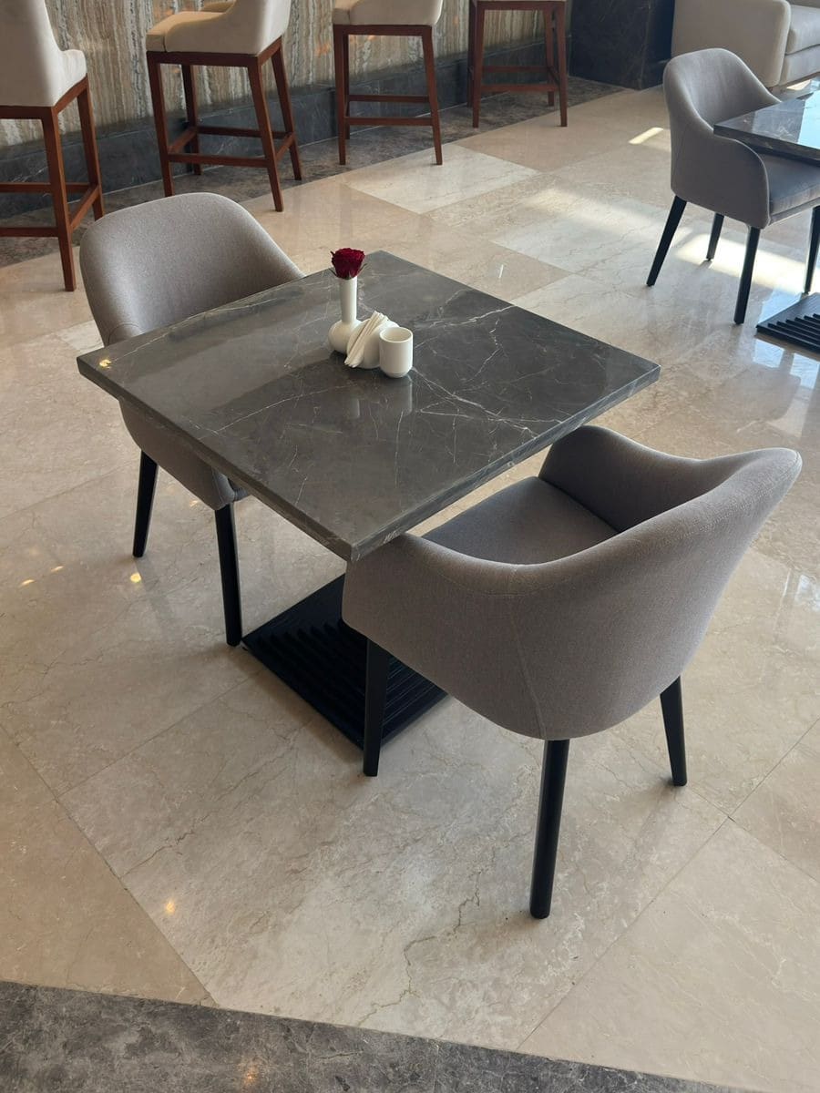 A marble dining table and upholstered chairs in a Rixos Montaza restaurant